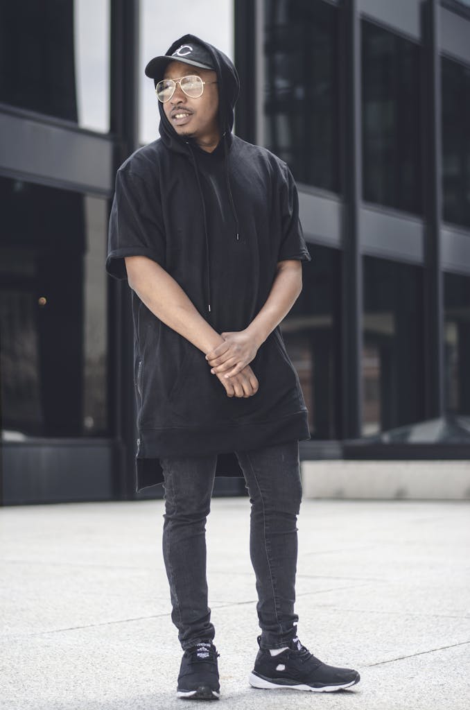 Fashionable young man posing confidently outdoors in black casual wear, embodying urban lifestyle.