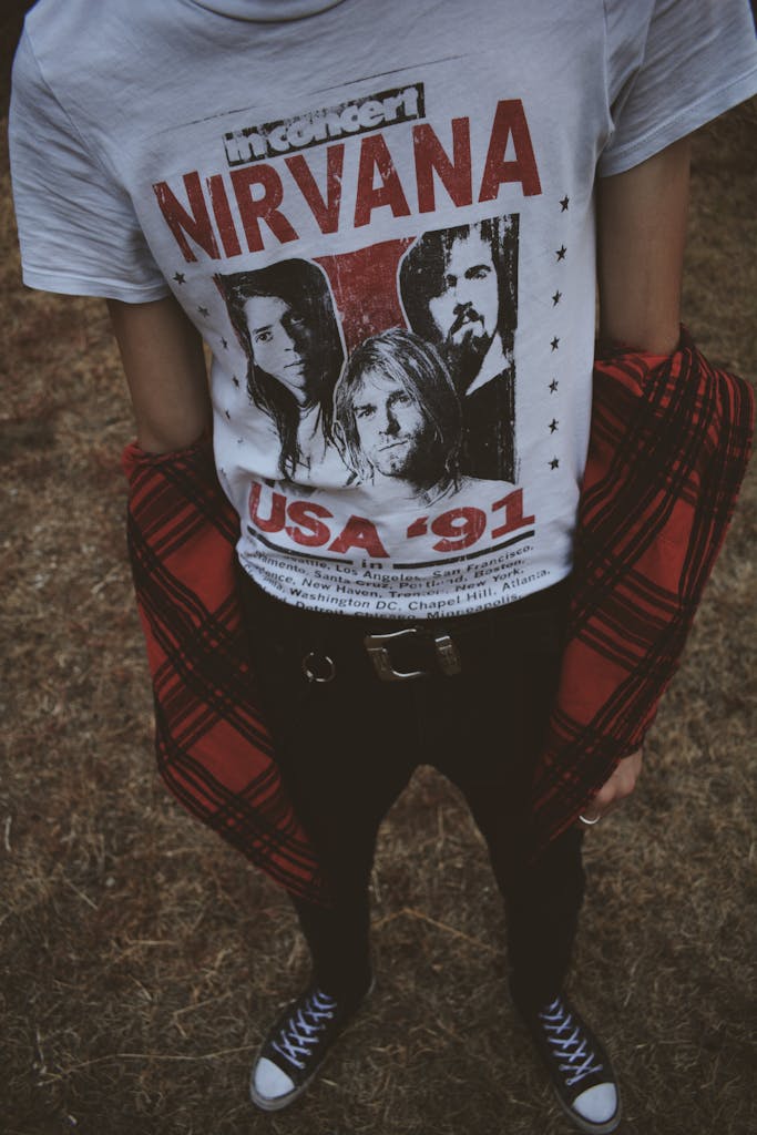 Person wearing a Nirvana t-shirt styled with black jeans and sneakers.